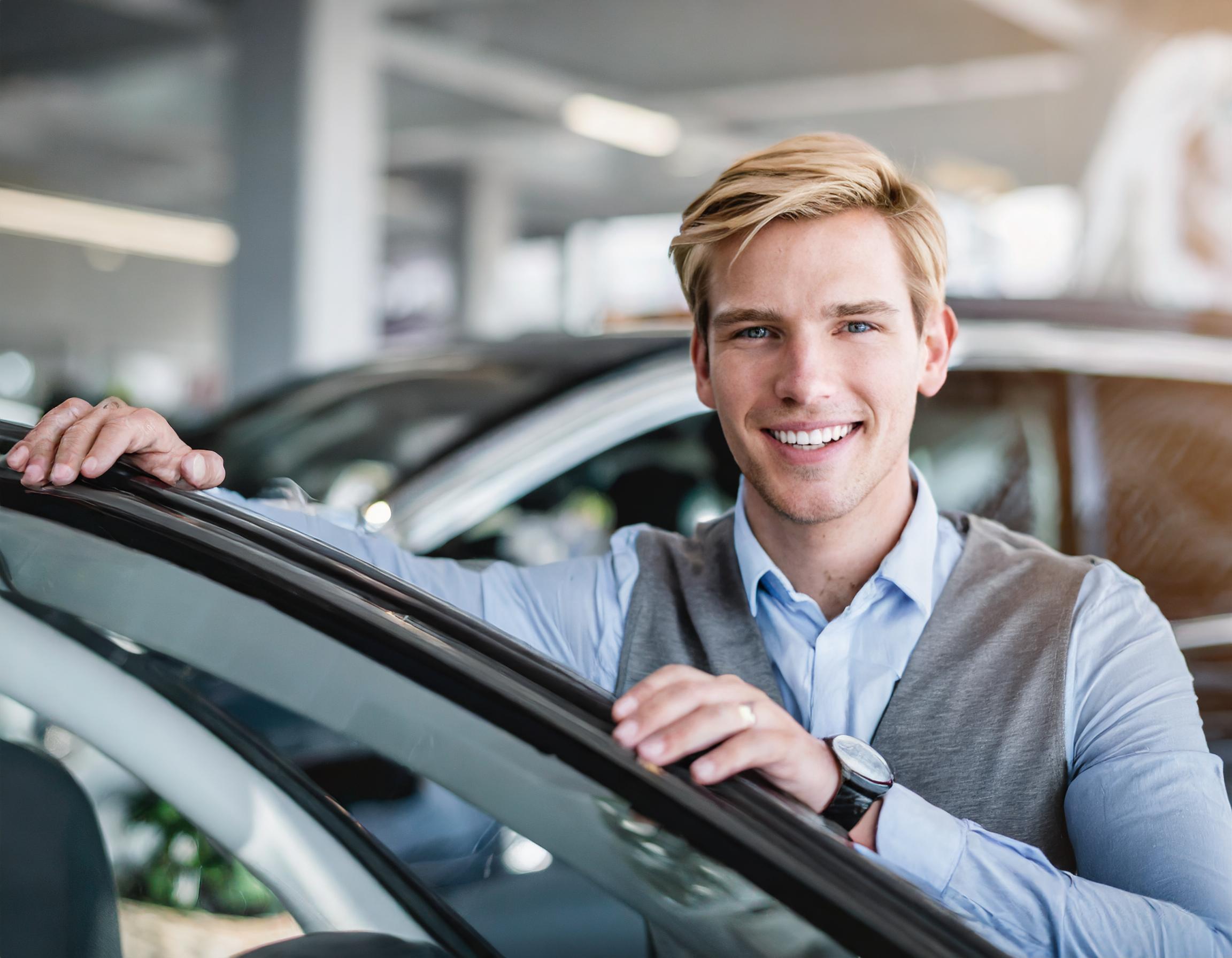 Teammitglied, das freundlich lächelt und ein Fahrzeug inspiziert